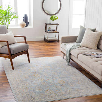 Living room scene with a Coby Deep Teal Avant Garde rug, beige sofa, gray chair, wood floors, and natural light. Roomscene-Rectangle