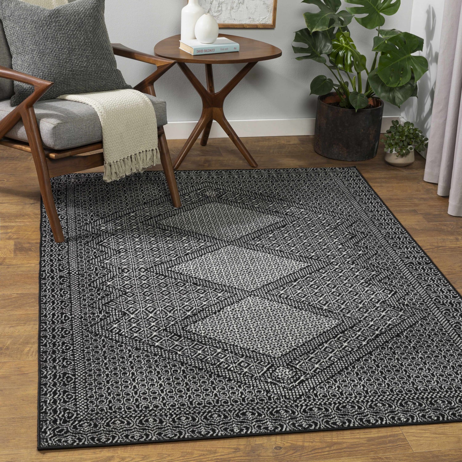 Living room scene with a gray chair, side table, and the Merkez Area Rug in a geometric gray and natural pattern. Roomscene-Rectangle
