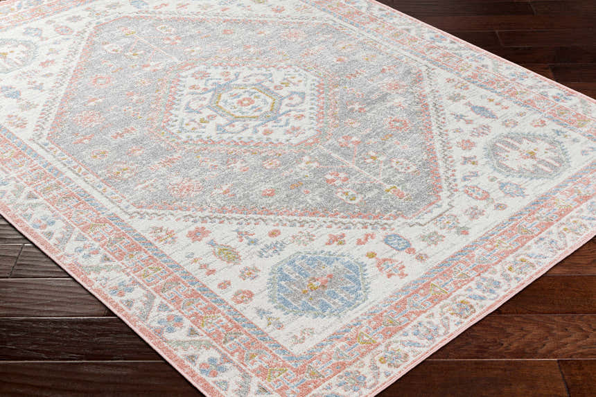 Close-up of Maha Washable Area Rug. Farmhouse style rug in bone, faded driftwood, mocha, and steel colors. Traditional pattern. Corner