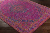 Close-up of the Milliken Magenta Area Rug. Features a traditional design in burgundy, navy, teal, and burnt orange on dark wood floors. Corner