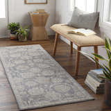 Entryway with a gray Mimarsinan Traditional rug, wood bench, books, and plants for a cozy, inviting feel. Roomscene-Runner
