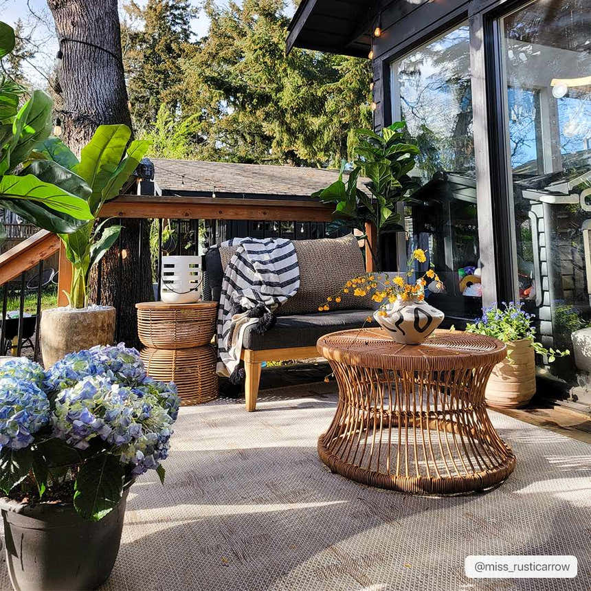 Outdoor patio scene with Limbo Beige area rug, wicker furniture, potted plants, and a cozy, inviting atmosphere. Roomscene-Rectangle