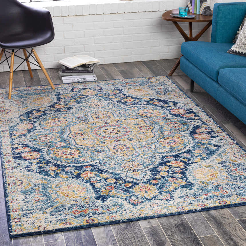 Living room scene with a blue sofa and the Mallacoota Area Rug in cream, pink, blue, and yellow. Roomscene-Rectangle