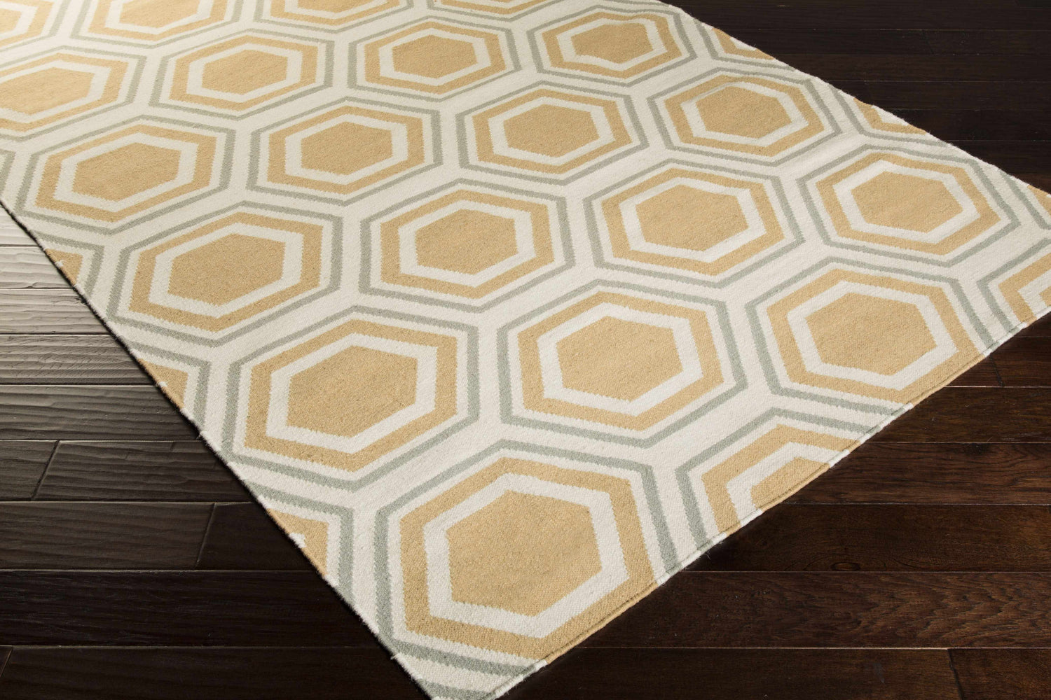 Close-up of Millstone Area Rug. Hand-woven wool rug with light beige, sage, and tan geometric hexagon pattern. Corner