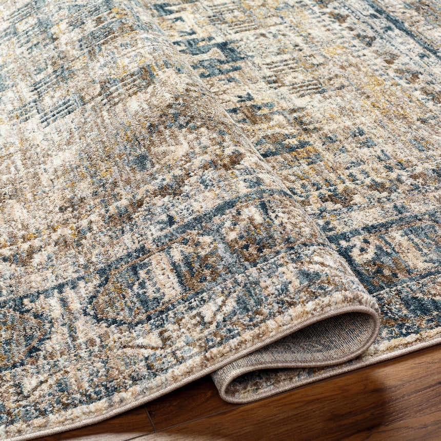 Close up of the Mundesley Area Rug showing its cream, blue, brown, and mustard traditional pattern. Fold
