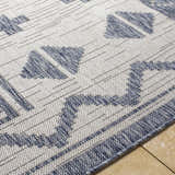 Close-up of the Mangoso Gray Area Rug showcasing its blue geometric pattern and woven texture on a tile floor. Texture