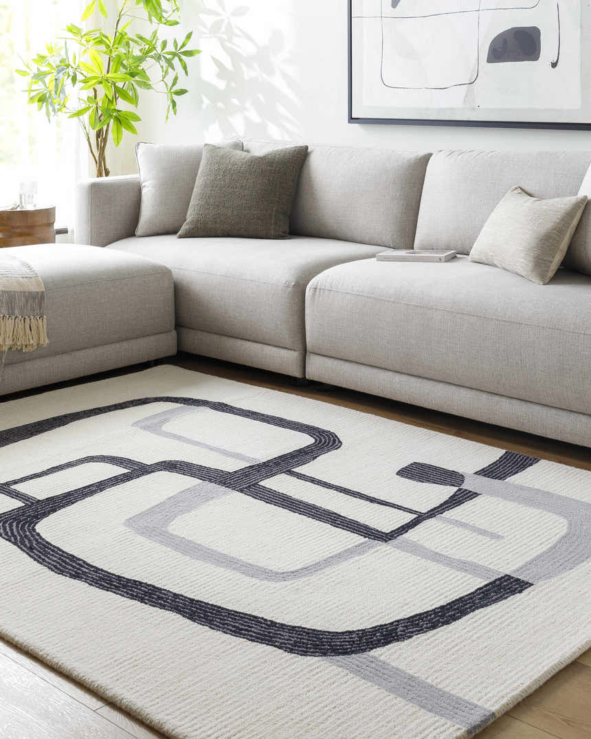 Living room with a gray sectional sofa and the Ulfah Area Rug, a contemporary wool rug with a geometric ash and black design. Roomscene-Rectangle