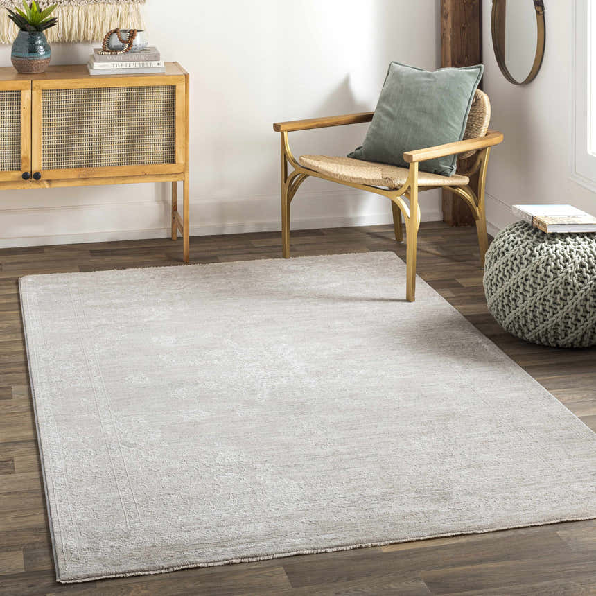 Light gray Monto Luxe rug in a neutral living room with wood floors, cabinet, chair, and olive green pouf. Roomscene-Rectangle