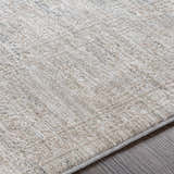 Close-up of the Monto Luxe Rug, a machine-woven rug in cream, tan, and gray with a subtle traditional pattern. Texture