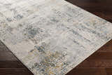 Close-up of Montreat Luxe Rug with cream, gray, teal, and mustard abstract pattern on dark wood floor. Corner