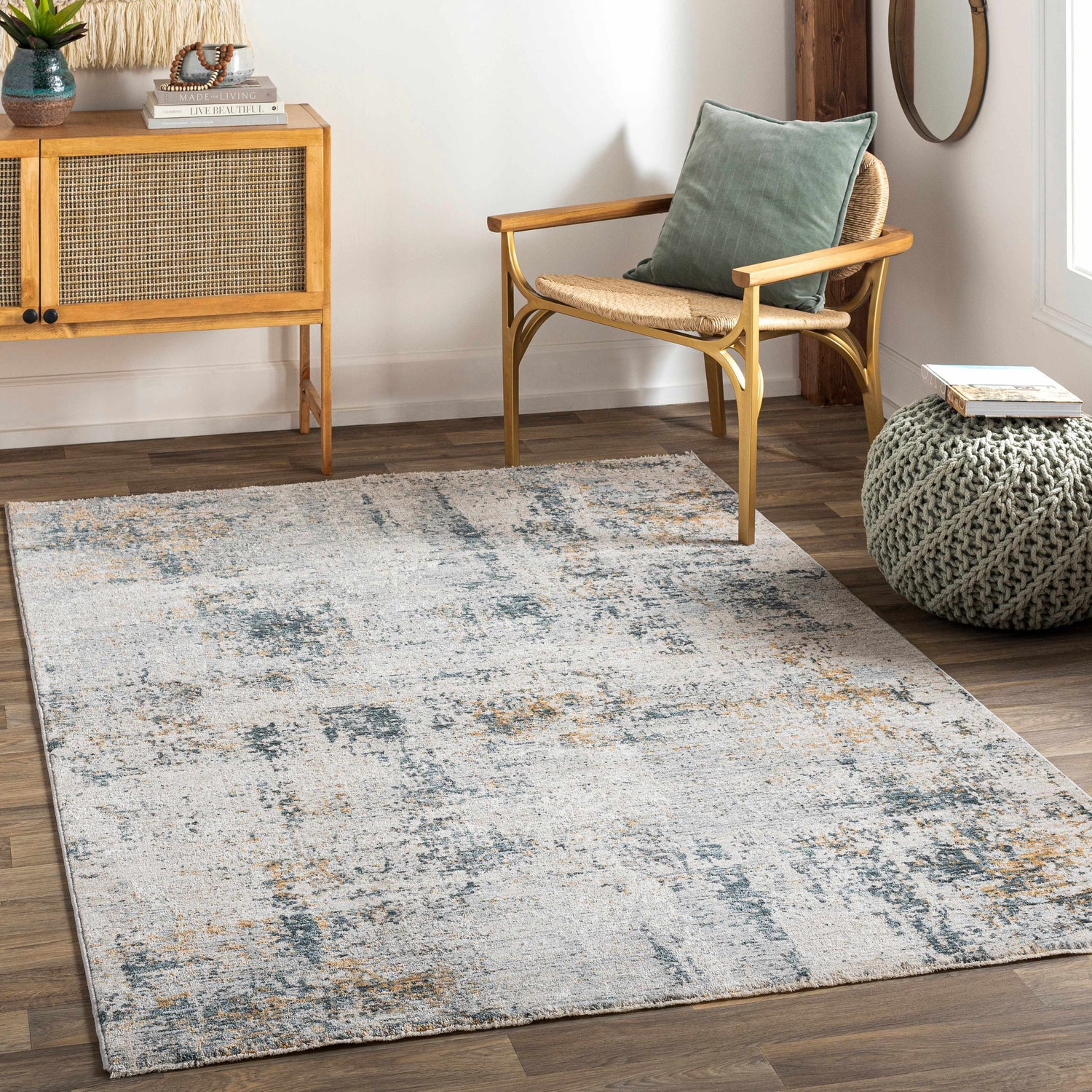 Living room scene with a cream, dusty sage, and gray Montreat Luxe Rug, wood floors, and a woven chair. Roomscene-Rectangle