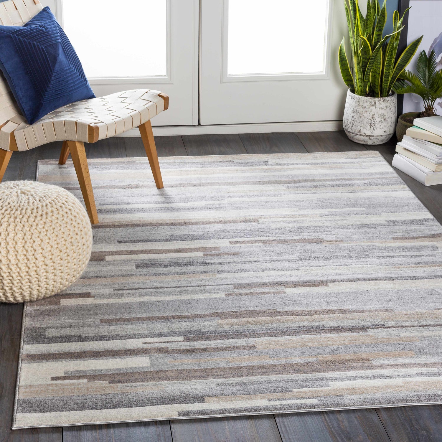 Entryway scene with a Monkland Area Rug in charcoal, gray, light gray, tan, and white. Modern chair and pouf. Roomscene-Rectangle