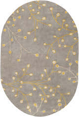Close-up of an oval Elsu Mustard Wool Area Rug. Features a gray background with a mustard and taupe floral branch pattern. Design-Oval-69