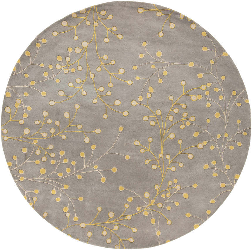 Close-up of the round Elsu Mustard Wool Area Rug, featuring a gray background and a delicate floral pattern in mustard and taupe. Design-Round-8