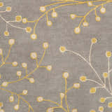 Close-up of Elsu Mustard Wool Area Rug featuring a floral branch pattern in mustard and taupe on a charcoal background. Swatch