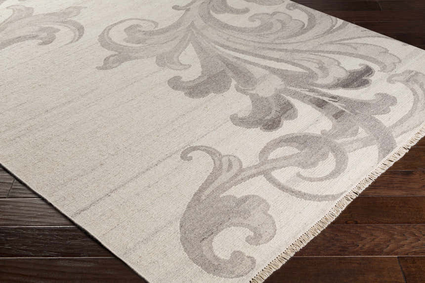 Close up of the Moorhead Carpet, a hand-knotted wool rug in oatmeal with a dark brown floral pattern. Corner