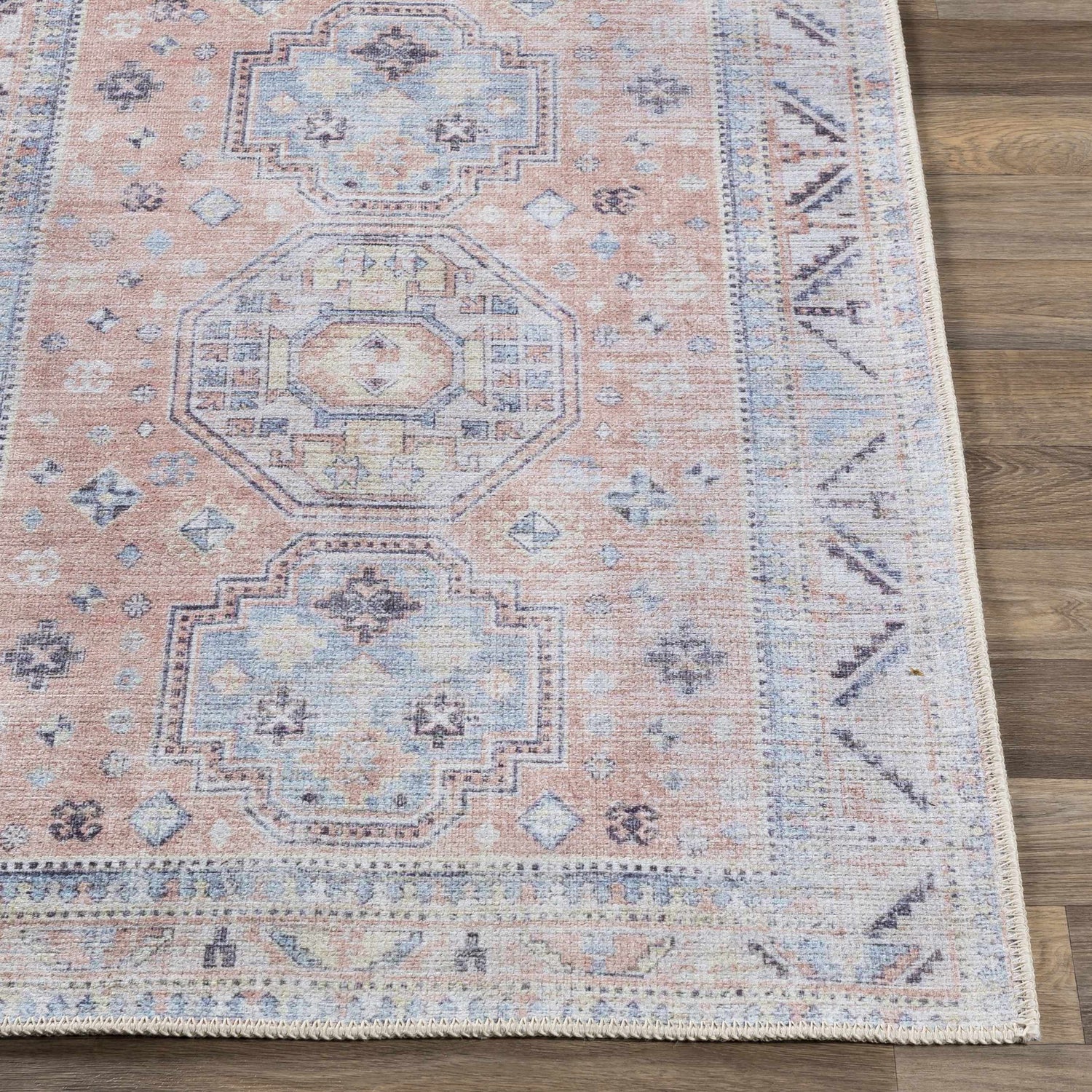 Close-up of the Morcott Peach Washable Area Rug, featuring a traditional design with peach, blue, and ivory tones. Front