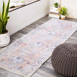 Hallway scene with Morcott Peach Washable Area Rug, plants, books, and a knitted ottoman. Roomscene-Runner