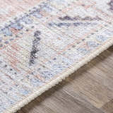 Close-up of Morcott Peach Washable Area Rug, showing chenille-polyester texture and bohemian-inspired pattern in peach, blue, and ivory. Texture