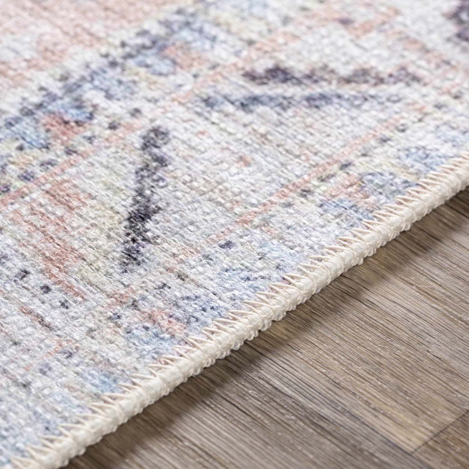 Close-up of Morcott Peach Washable Area Rug, showing chenille-polyester texture and bohemian-inspired pattern in peach, blue, and ivory. Texture