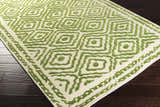 Close-up of the Morehead Area Rug. Hand-knotted wool rug in grass green and light beige with a geometric diamond pattern. Corner