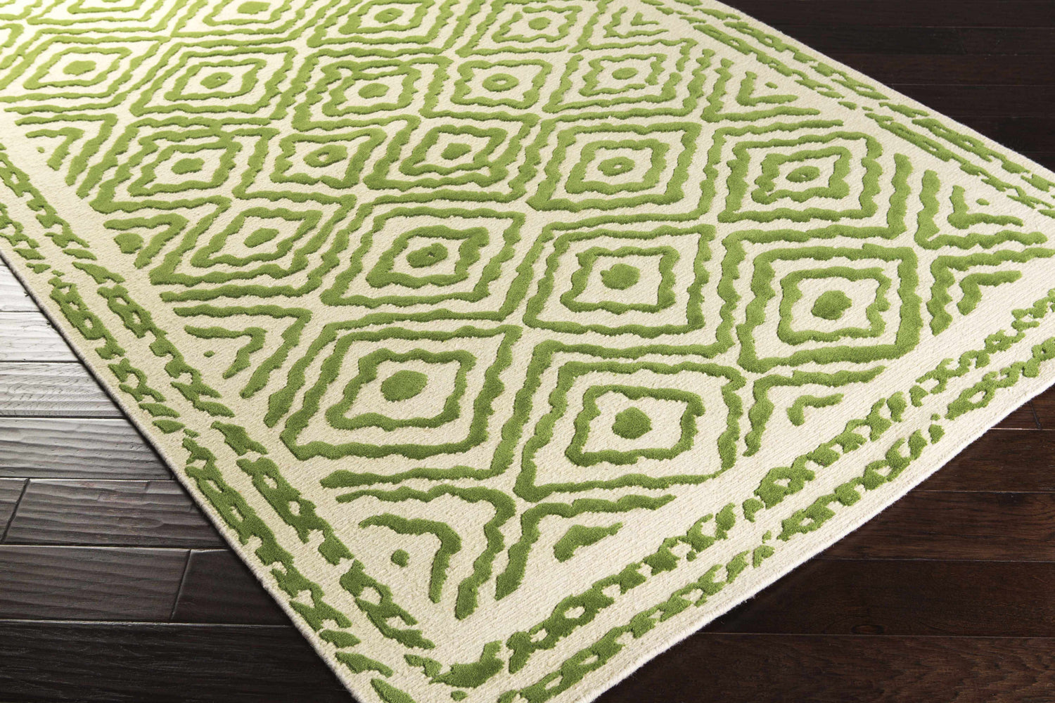 Close-up of the Morehead Area Rug. Hand-knotted wool rug in grass green and light beige with a geometric diamond pattern. Corner