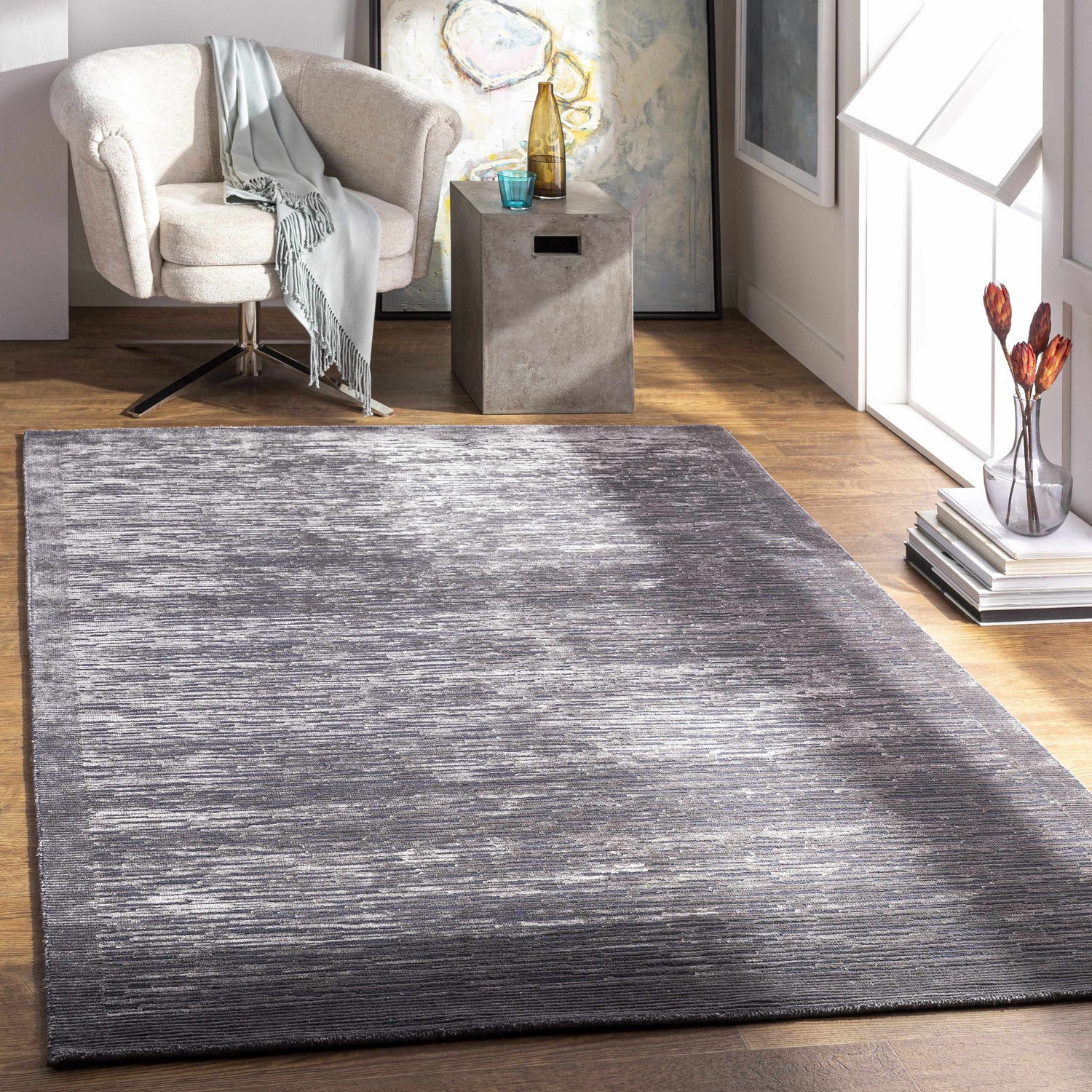 Contemporary living room with a black and charcoal Motcombe Area Rug, beige chair, and wood floors. Roomscene-Rectangle
