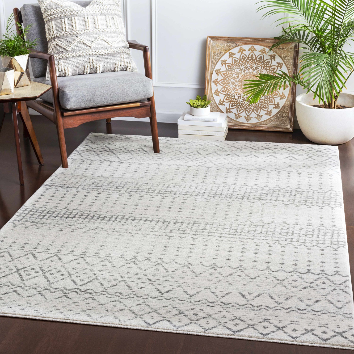 Living room scene with a Moweaqua Area Rug in charcoal, gray, and ivory, styled with a chair, plant, and decorative art. Roomscene-Rectangle