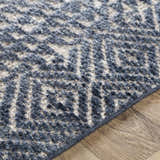 Close-up of the hand-knotted Moyne Area Rug. Charcoal, dark blue, and white geometric pattern. Bohemian style. Pile