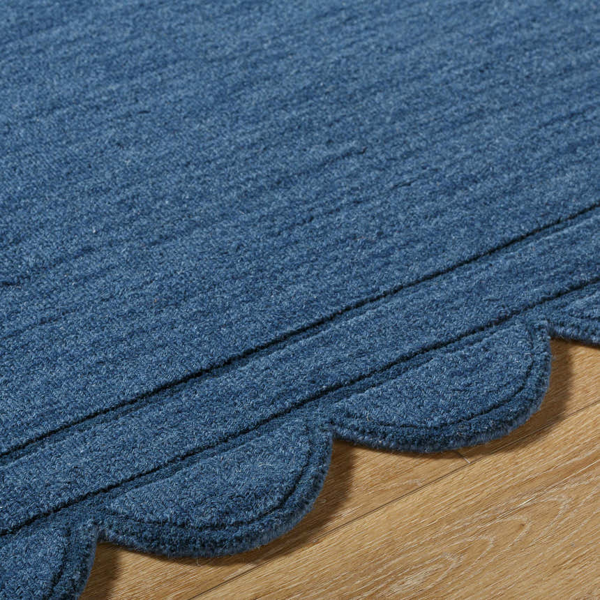 Close-up of the hand-loomed Uhuro Blue Geometric Area Rug showing wool texture and the rug's unique scalloped edge. Texture