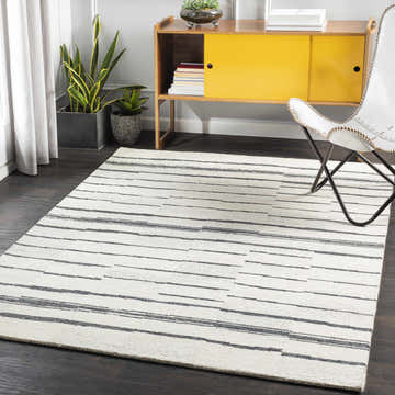 Living room scene with a Moorebank Black Striped Wool Rug, yellow mid-century cabinet, white chair, and dark wood floors. Roomscene-Rectangle