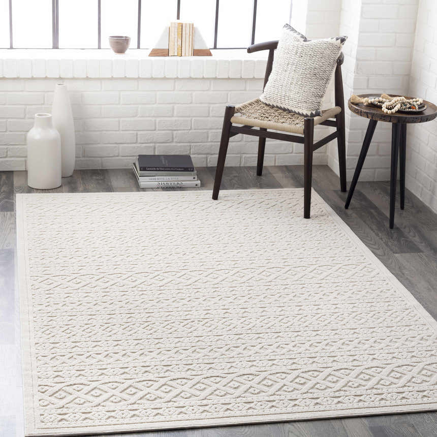 Living room scene with a cream Maribyrnong 3D Outdoor Area Rug, chair, and side table against a white brick wall. Roomscene-Rectangle
