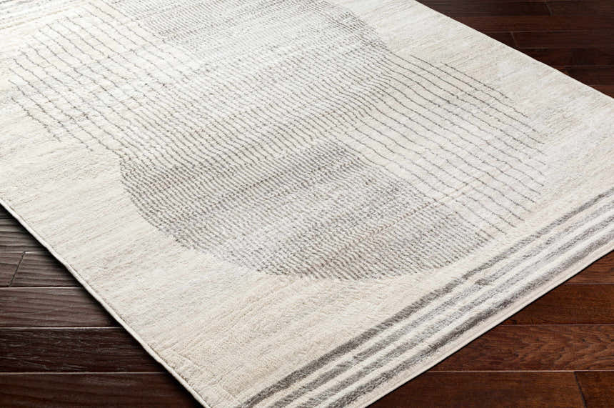 Close-up of the Amar Area Rug in shades of gray and natural on dark wood floors, featuring a contemporary geometric pattern. Corner