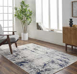 Living room scene with a charcoal, light gray, and navy Marwa Area Rug, gray chair, and wood cabinet. Roomscene-Rectangle