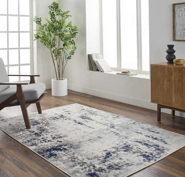 Living room scene with a charcoal, light gray, and navy Marwa Area Rug, gray chair, and wood cabinet. Roomscene-Rectangle