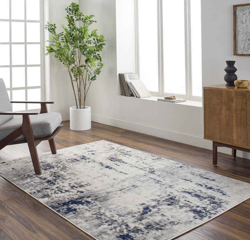 Living room scene with a charcoal, light gray, and navy Marwa Area Rug, gray chair, and wood cabinet. Roomscene-Rectangle