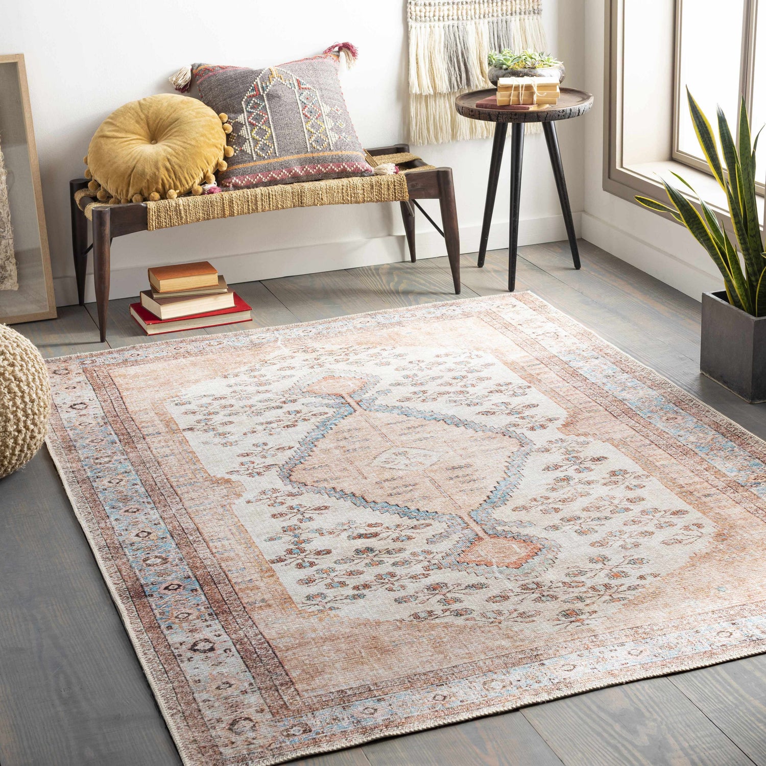 Cozy living room scene with a beige and blue Oriental style Moora Washable Area Rug, bench, pillows, and houseplant. Roomscene-Rectangle