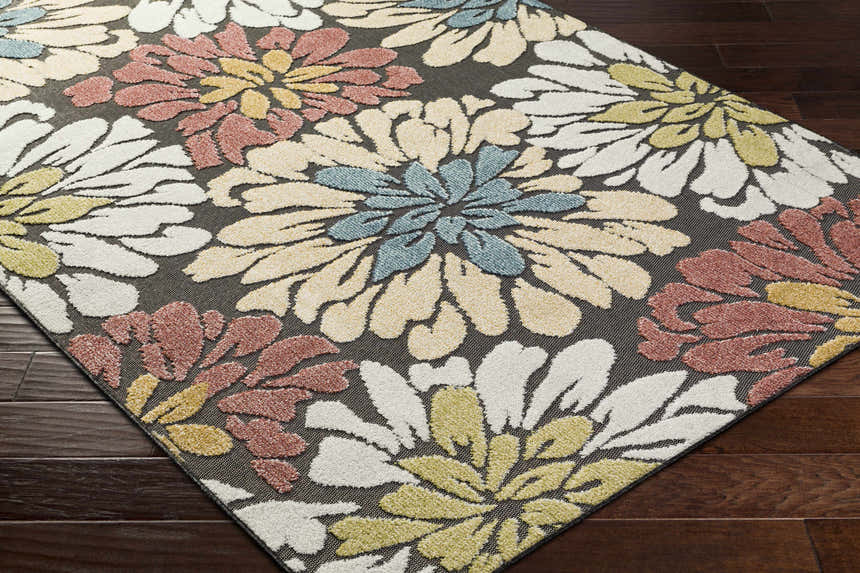 Close-up of Minga Charcoal Area Rug. Floral pattern in cream, navy, olive, rust, and tan on a charcoal background. Corner