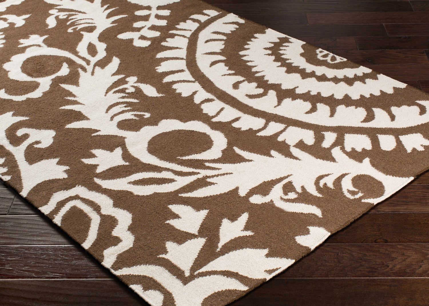 Close-up of the Naeva Area Rug, a hand-woven wool rug in dark brown and white with a contemporary floral pattern. Corner