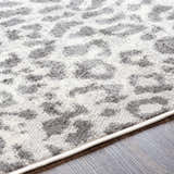 Close-up of the Nagambie Leopard Print Area Rug. Features a gray and light gray animal print pattern on a white background. Texture