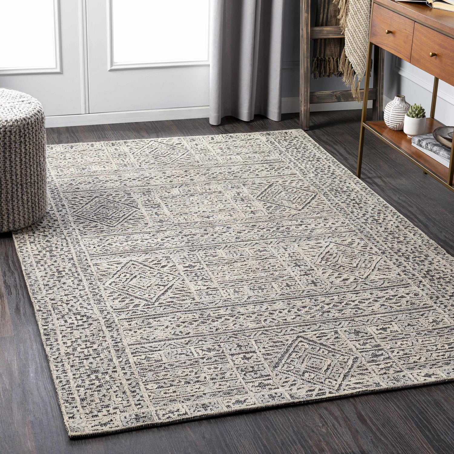 Living room scene with Nairne Textured Wool Area Rug in black, gray, and taupe. Bohemian style on dark wood floors. Roomscene-Rectangle