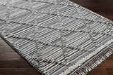 Close-up of the Nairobi Area Rug. Black, gray, and ivory striped wool rug with a hand-knotted texture. Corner