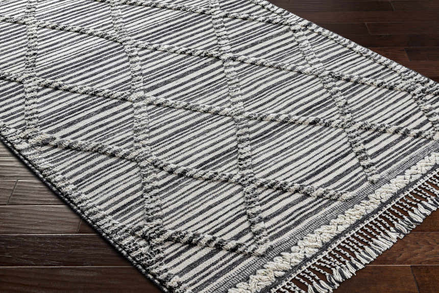 Close-up of the Nairobi Area Rug. Black, gray, and ivory striped wool rug with a hand-knotted texture. Corner