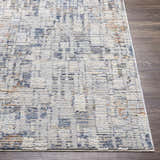 Close-up of the Nalus Area Rug showing its brick red, cream, denim, and gray abstract design and soft texture. Front