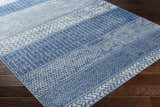 Close-up of the Nampa Area Rug in denim and ivory, featuring a contemporary geometric pattern on a dark wood floor. Corner