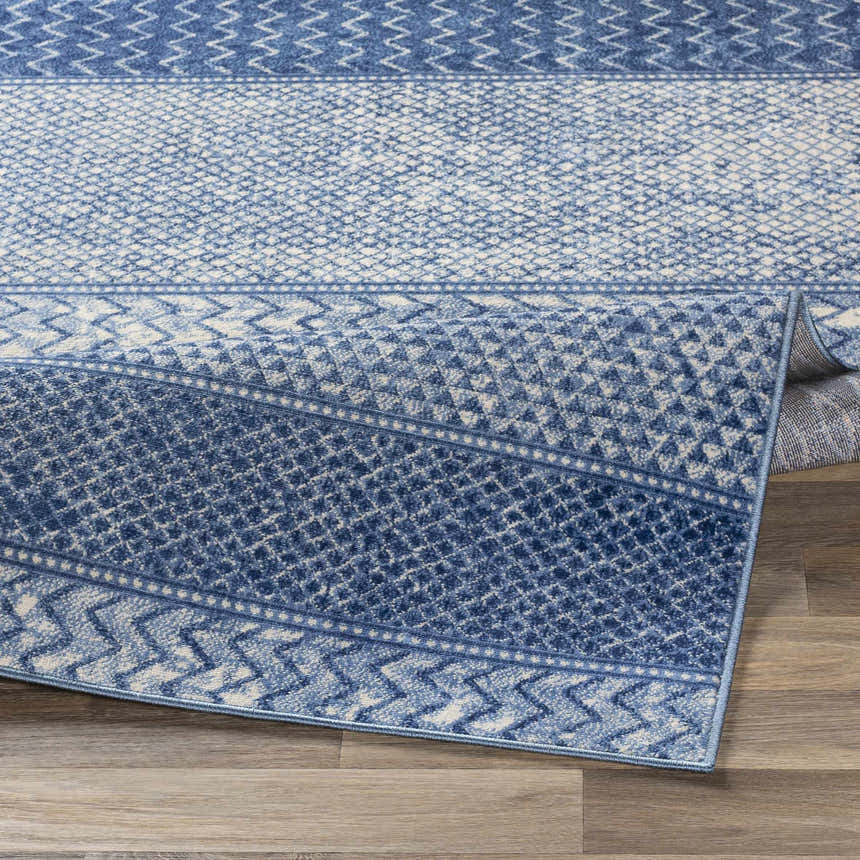 Close-up of the Nampa Area Rug showing its denim, ivory, and navy contemporary pattern and machine-woven texture. Fold