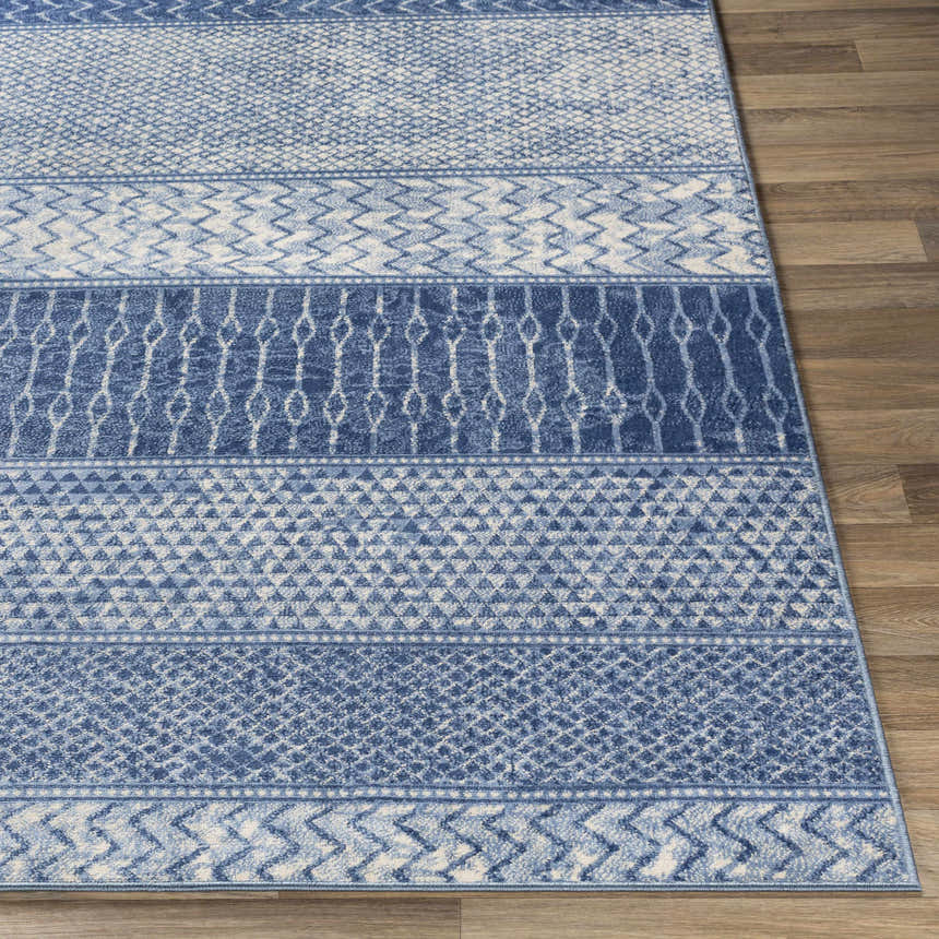 Close-up of the Nampa Area Rug in denim, ivory, and navy. Features contemporary geometric patterns on a wood floor. Front