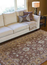 Living room scene with a neutral sofa and the brown floral Napolville Premium Wool Area Rug. Roomscene-Rectangle