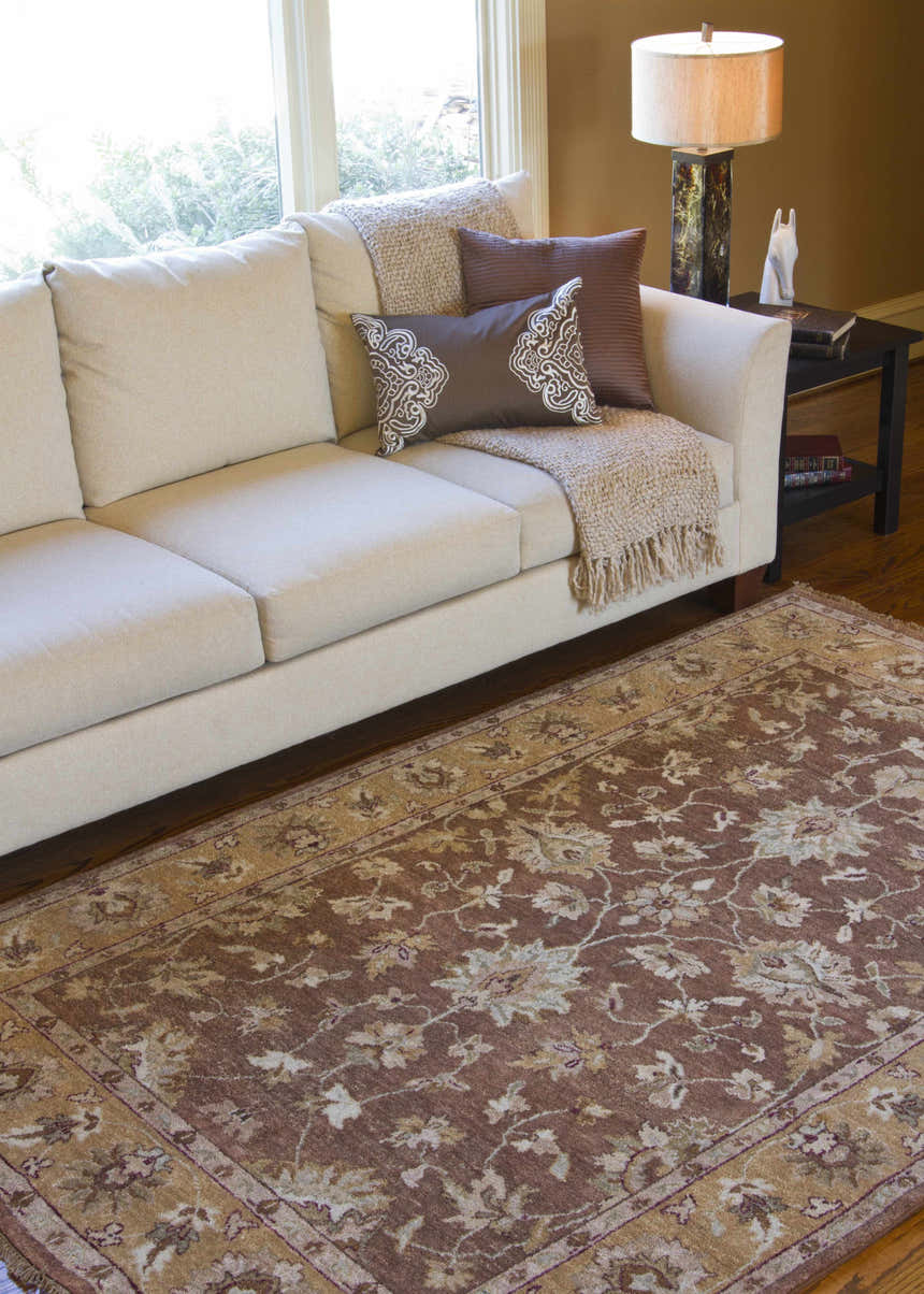 Living room scene with a neutral sofa and the brown floral Napolville Premium Wool Area Rug. Roomscene-Rectangle