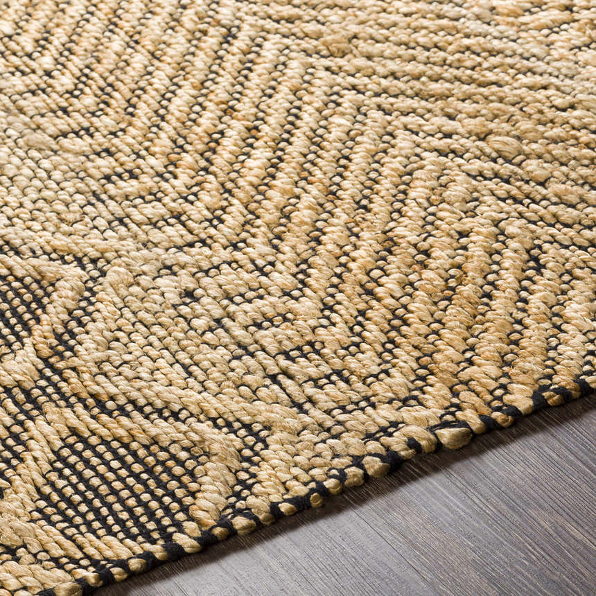 Close-up of the hand woven Nasugbu Jute Carpet. Tan jute rug with a black geometric pattern and natural texture. Texture